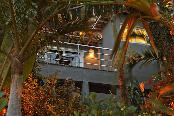 A multi-level atrium with lush tropical plants, a stone lion statue, and a balcony with a railing. - La Suite by Dussol (Rio de Janeiro)