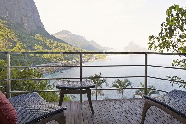 Een balkon met rieten meubilair, met uitzicht op een rivier en bergen.