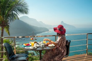 Iemand geniet van een maaltijd aan een tafel met uitzicht op de oceaan en bergen.