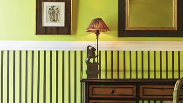 A room with a green wall, a wooden bench, a lamp, and framed pictures.