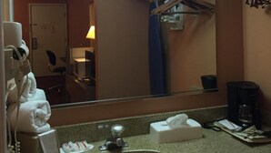 A hotel bathroom with a sink, mirror, and towel rack.