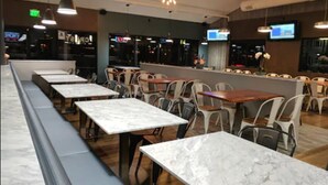 A restaurant with marble-topped tables and chairs, pendant lighting, and a bar area. - The Atwood Hotel San Diego - SeaWorld/Zoo (San Diego)