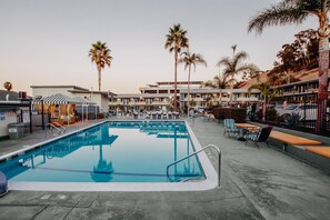 A swimming pool with lounge chairs and umbrellas, surrounded by palm trees and a building with multiple balconies. - The Atwood Hotel San Diego - SeaWorld/Zoo (San Diego)