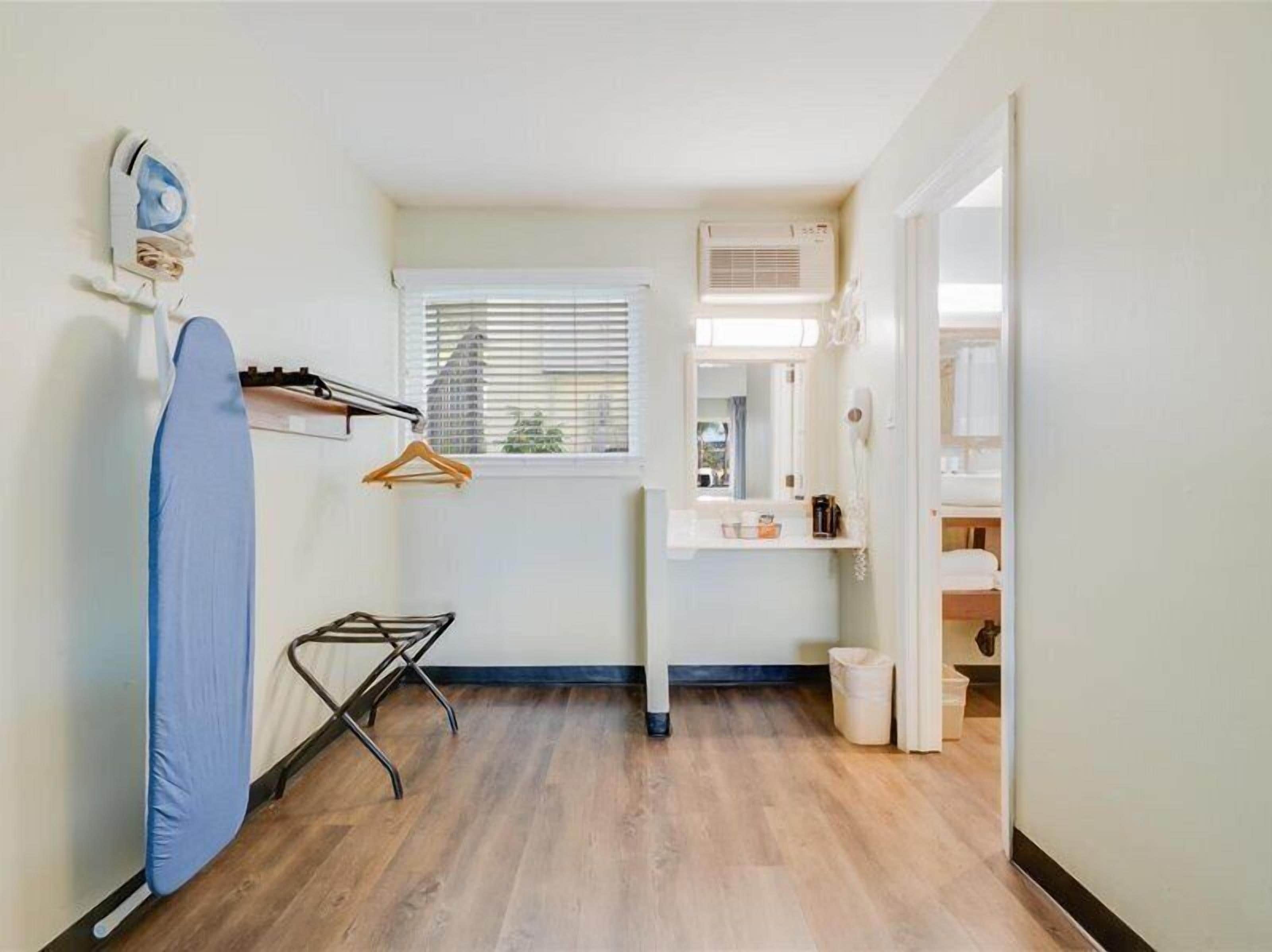 A compact kitchen with a window, a drying rack, and a hanging iron.