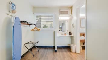 A compact kitchen with a window, a drying rack, and a hanging iron.