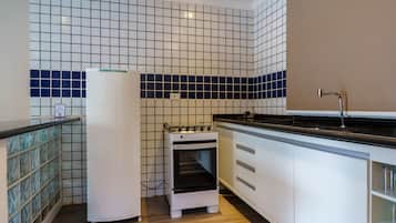 Uma cozinha compacta com armários brancos, bancada preta e forno embutido.