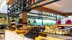 A bakery counter with various pastries and baked goods, shelves with bottles, and a seating area with chairs. - Pousada Apple House Paraty (Paraty)