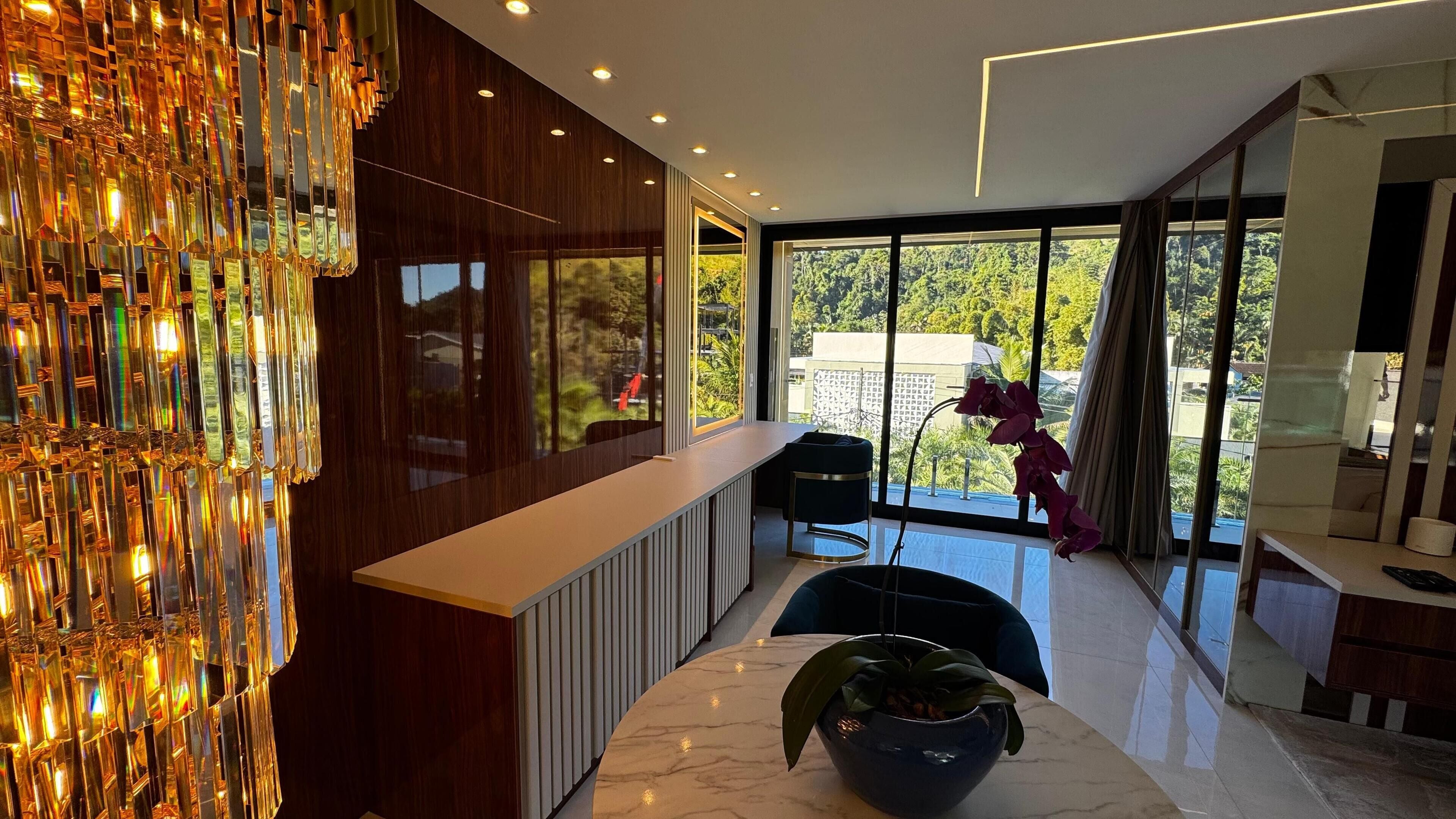 A modern interior with a marble countertop, a potted plant, and a view of greenery outside.