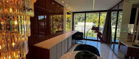 Un intérieur moderne avec un plan de travail en marbre, une plante en pot et une vue sur la verdure à l’extérieur.