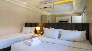 Una habitación de hotel con dos camas, una mesita de noche con lámpara y un aire acondicionado.