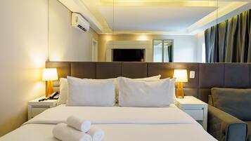 Habitación de hotel con una cama grande, dos mesitas de noche con lámparas, un televisor de pantalla plana y un espejo.