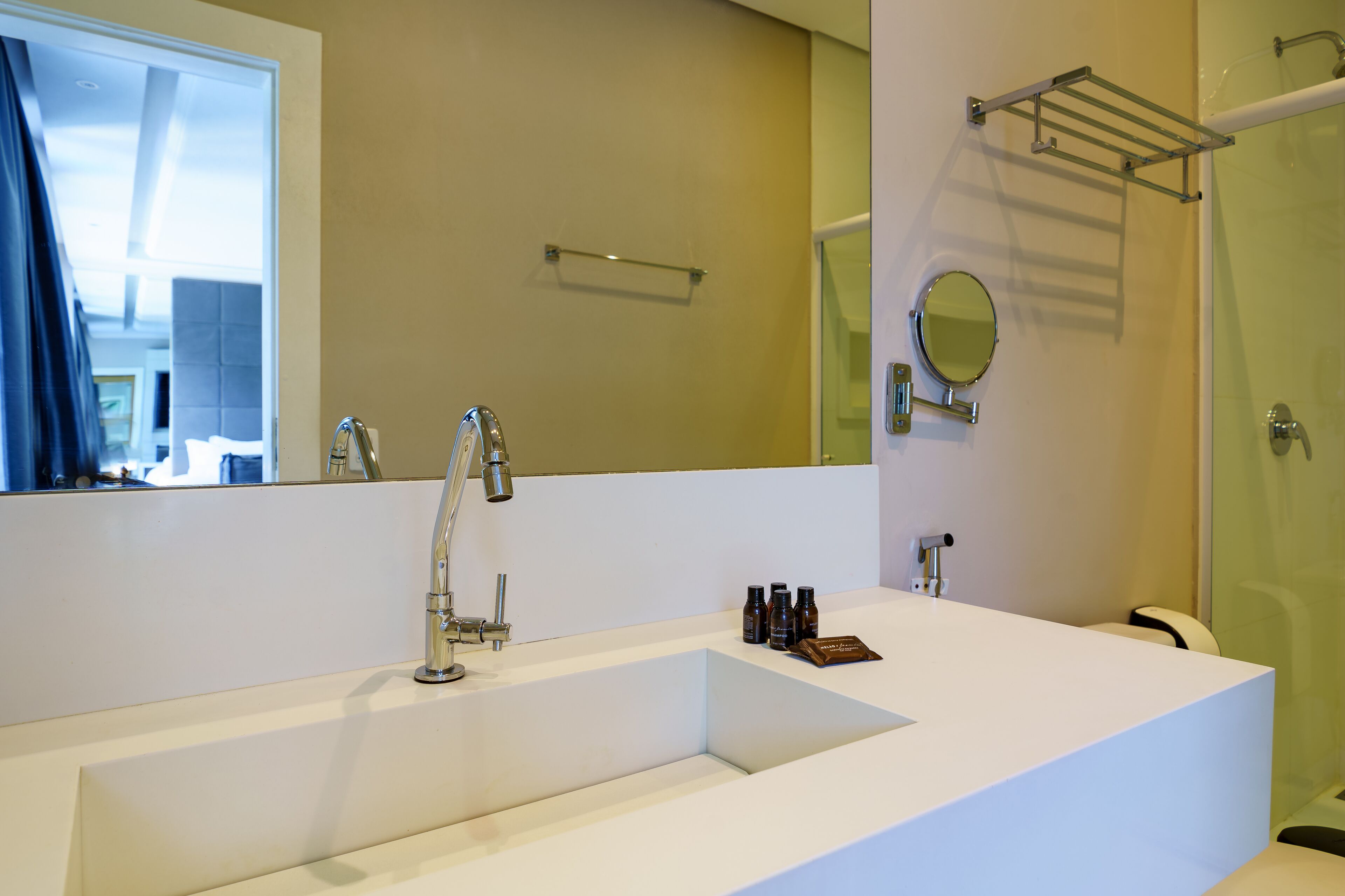 A modern bathroom with a large white sink, a mirror, and a glass shower enclosure.