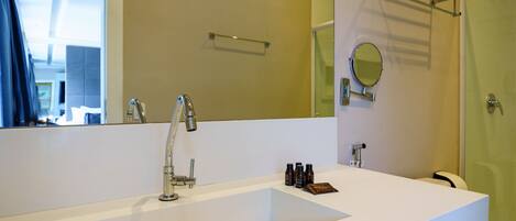 Un baño moderno con un lavabo blanco grande, un espejo y una cabina de ducha con mampara de vidrio.