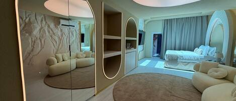 Une chambre d’hôtel moderne avec un grand miroir, un tapis rond, un canapé et un lit.