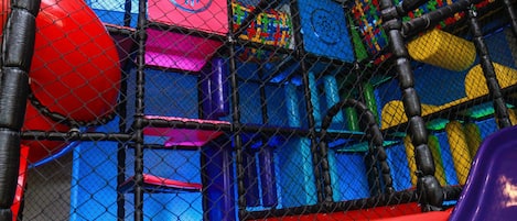 A colorful indoor play area with various play structures and a ball pit.