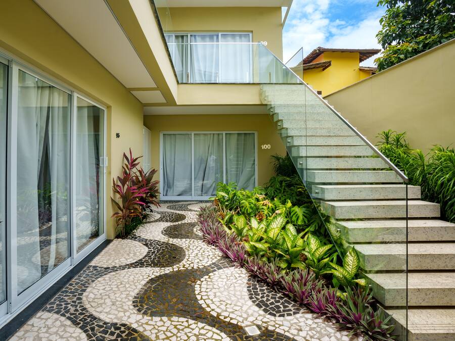 Una casa moderna con entrada empavedada, puerta de cristal y escalera que sube al piso superior.