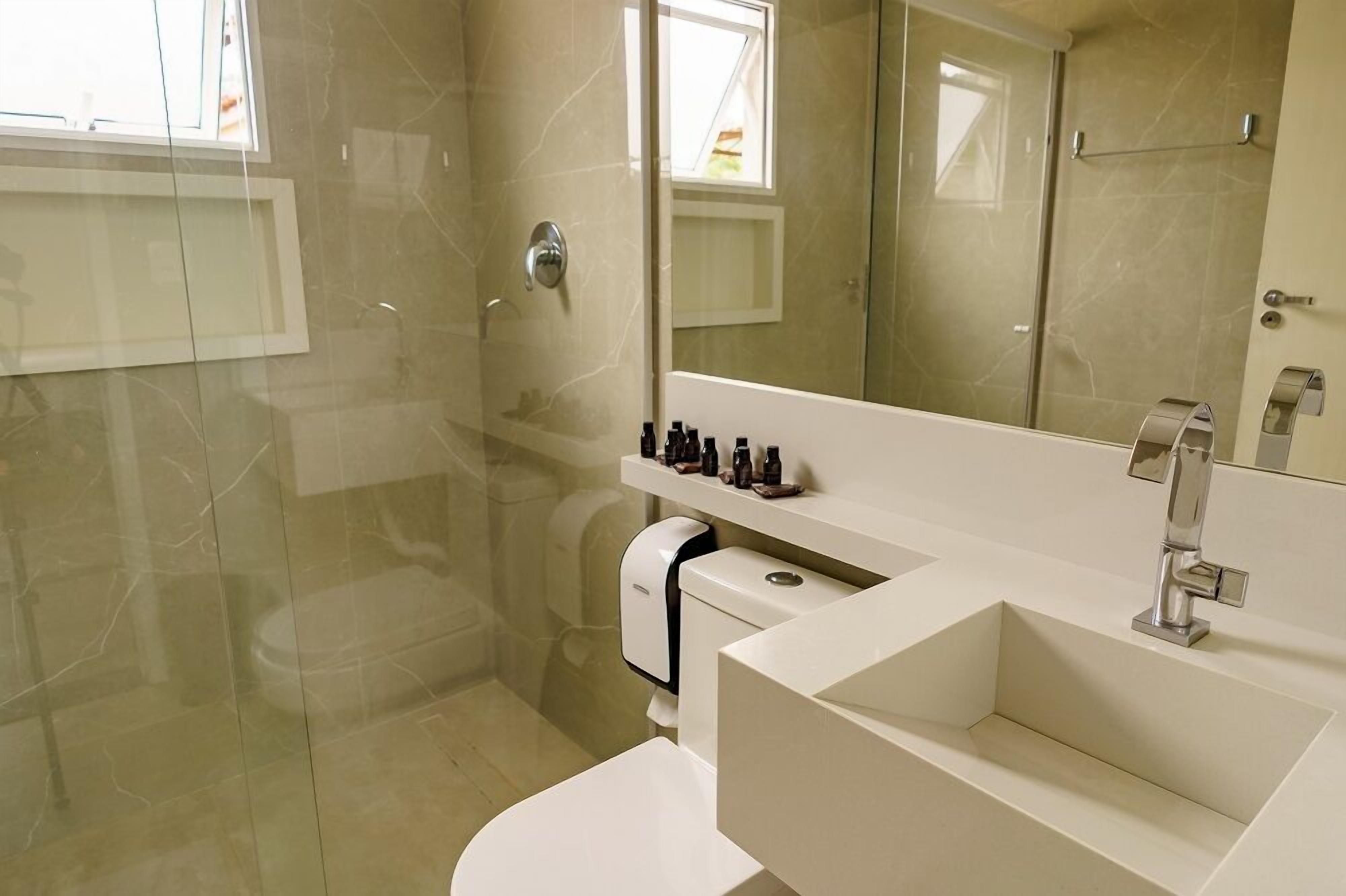 Un bany modern amb dutxa envidriada, un lavabo blanc i un mirall sobre la poció.