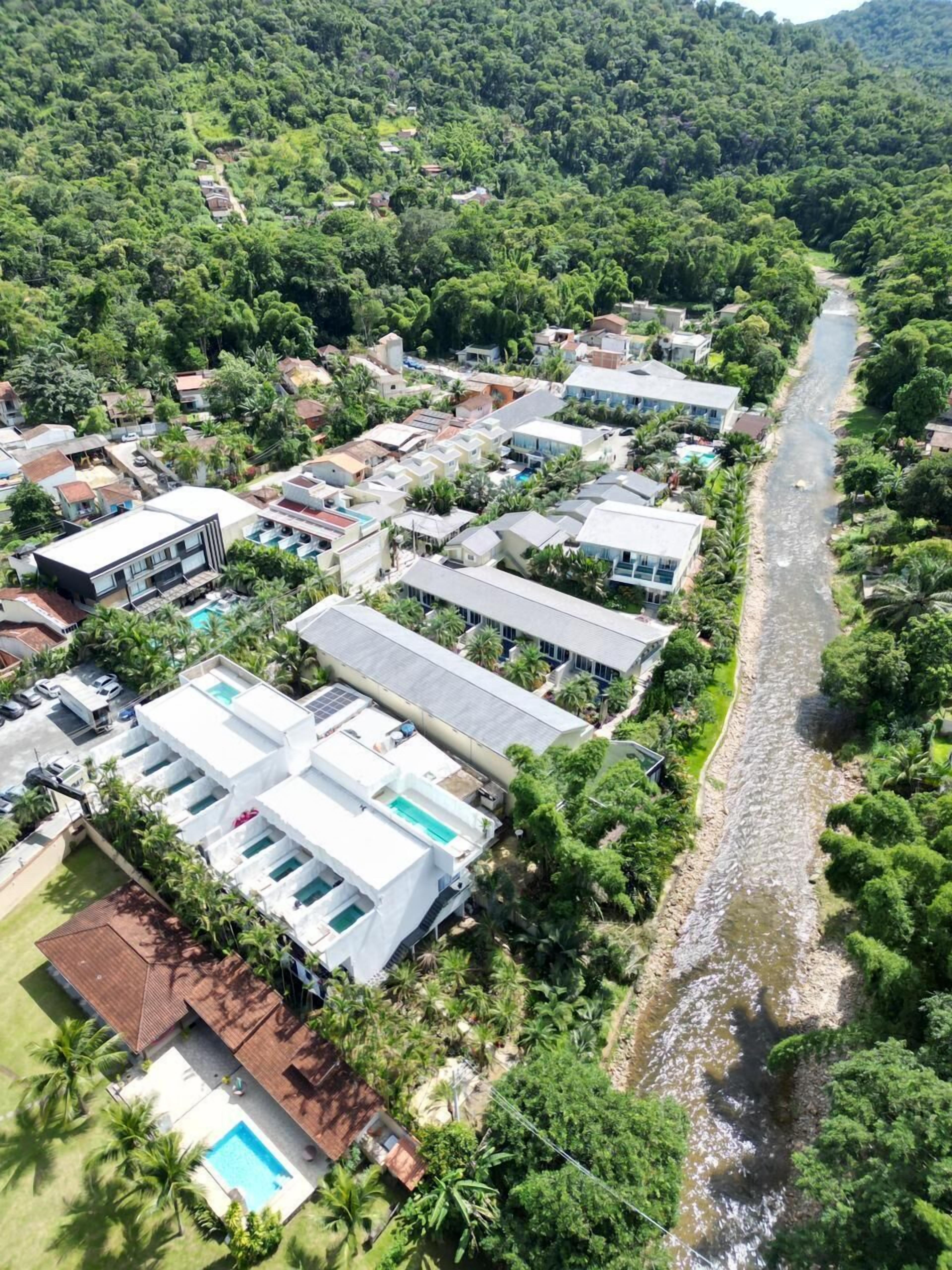 An aerial view of a residential area with houses, a river, and lush greenery.