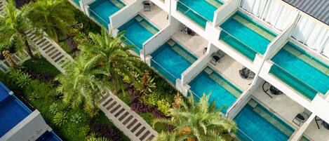 Ein mehrstöckiges Hotel mit mehreren Schwimmbecken, jeweils mit einer eigenen Liegefläche.