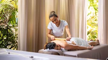 Una sesión de masoterapia en una habitación con cama, cortinas y una planta.
