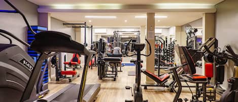 Une salle de sport équipée de tapis de course, d’appareils de musculation et de divers équipements d’exercice.