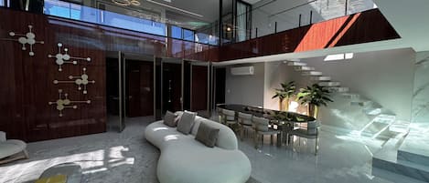 Un intérieur moderne avec un canapé blanc aux lignes courbes, un coin repas doté d’une table en verre et un escalier agrémenté d’éléments en bois.