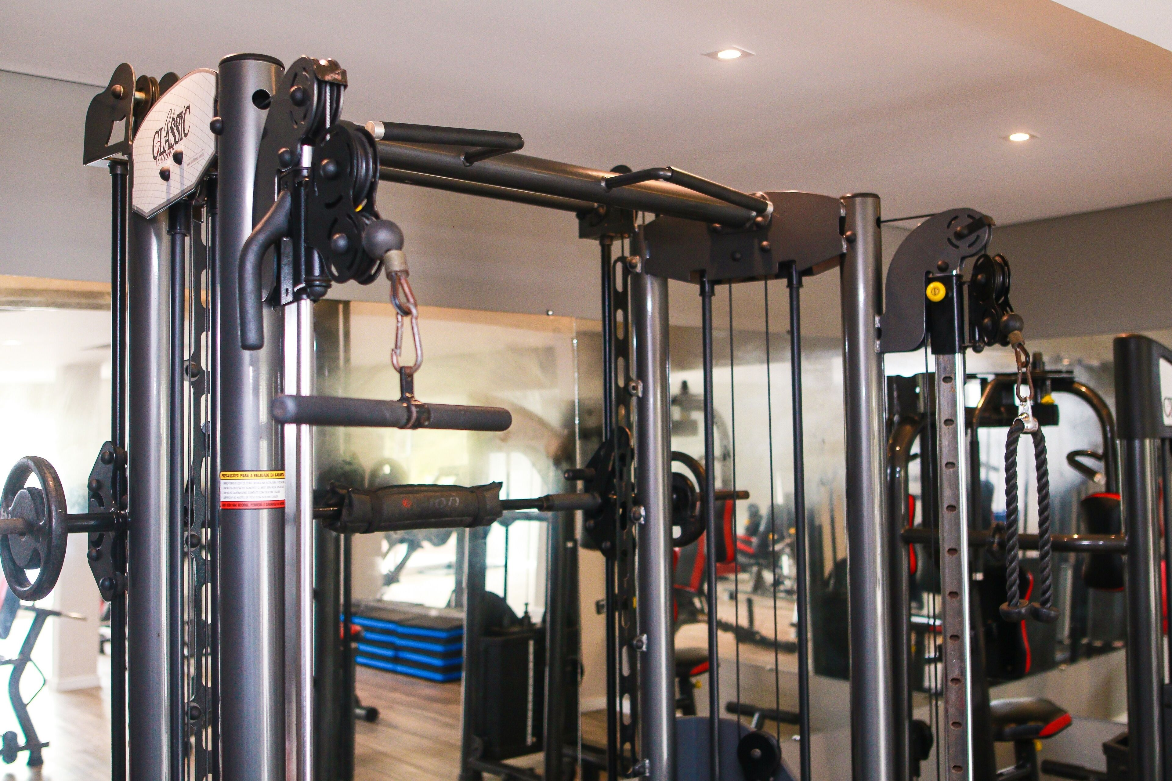 Une salle de sport équipée de divers appareils d'exercice, notamment une machine à câbles et des piles de poids.