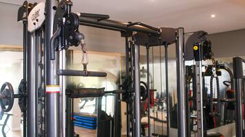 Une salle de sport équipée de divers appareils d'exercice, notamment une machine à câbles et des piles de poids.