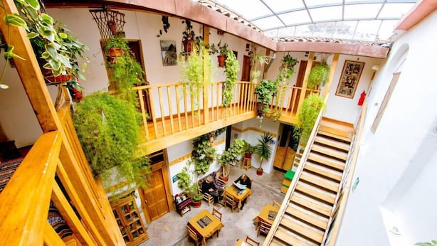 A multi-level atrium with wooden railings, potted plants, and seating areas. - Hostal El Grial (Cusco)
