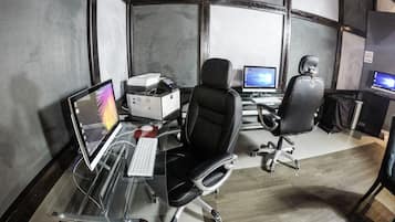 Una oficina moderna con dos escritorios, sillas, computadoras e impresora.