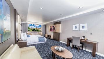Moderni hotellihuone, jossa on suuri sänky, työpöytä, tuoli ja pieni pöytä.