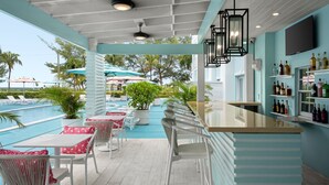 A poolside bar area with white chairs and tables, a bar counter, and a view of the pool. - Courtyard by Marriott Nassau Downtown/Junkanoo Beach (Nassau)