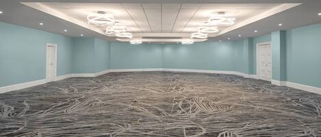 Una sala de conferències amb un mosaic de moqueta, il·luminació empotrada i parets de color blau clar.