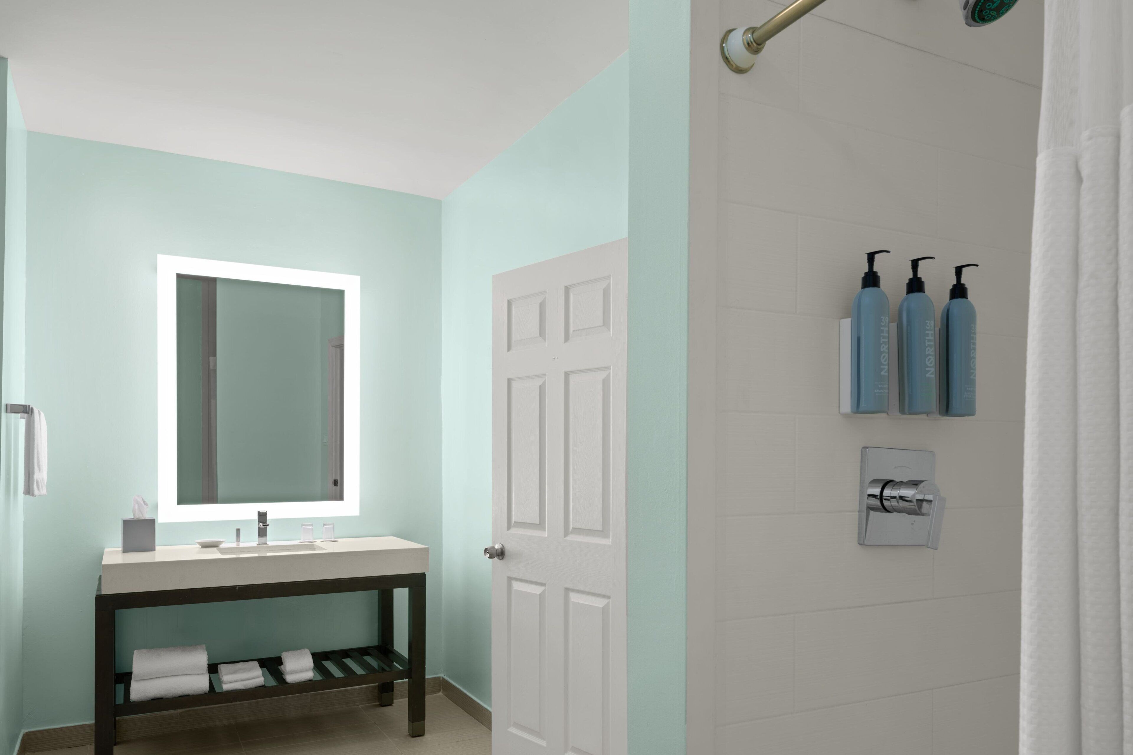 A bathroom with a sink, mirror, and shower area.
