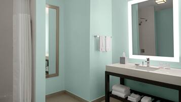Une salle de bain moderne avec un mur bleu clair, un grand miroir, un lavabo blanc et un espace douche.