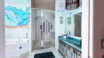 Une salle de bain moderne dotée d’une douche à parois de verre, d’un meuble-lavabo agrémenté d’un miroir décoratif et d’une grande fresque murale.