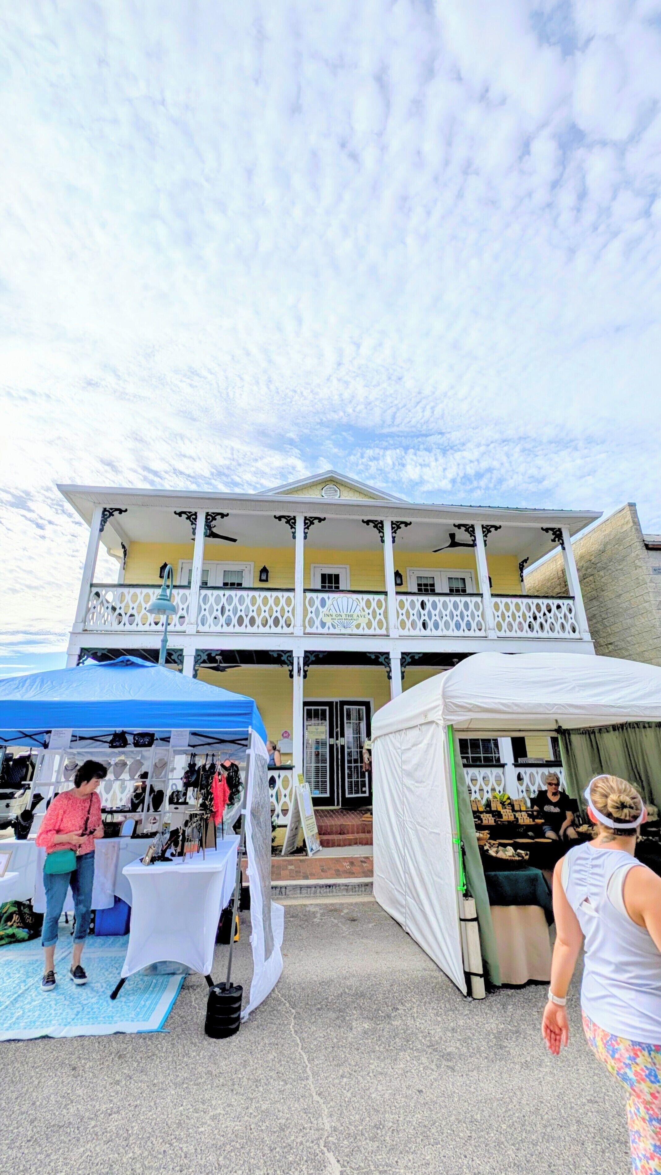 A two-story building with a balcony, a sign reading "Inn on the Ave," and a market stall in front.