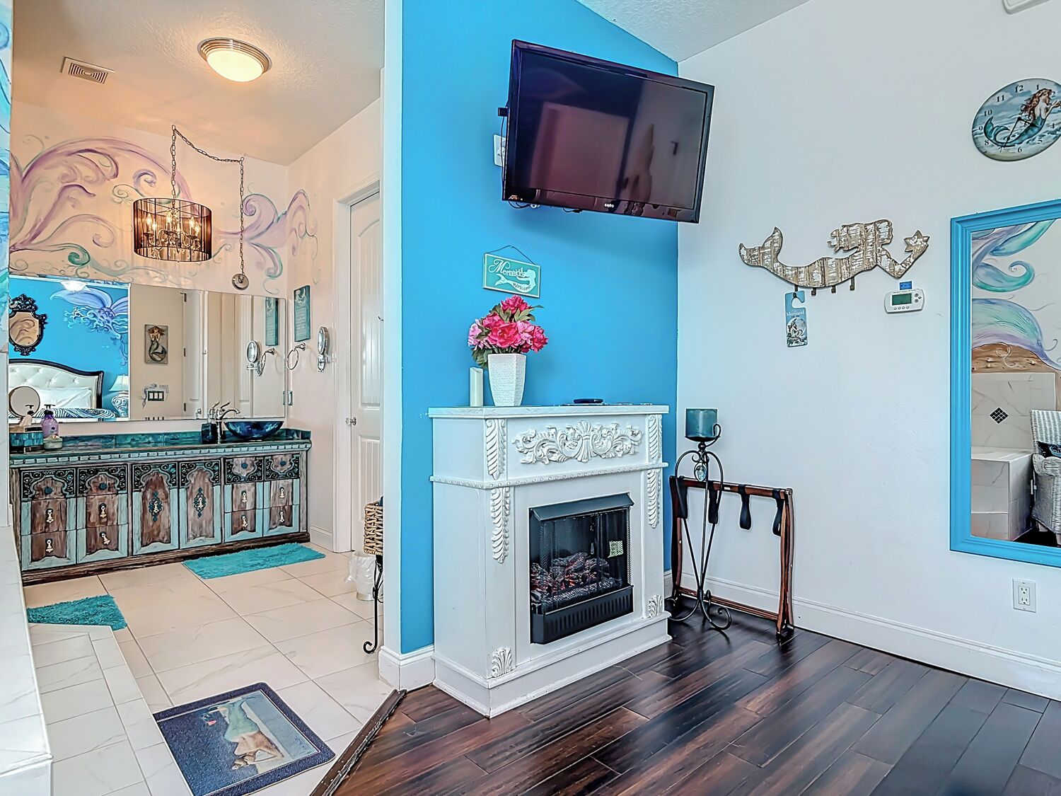 A living room with a fireplace, a mounted TV, and a blue accent wall.
