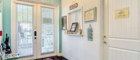 A hallway with a chandelier, a check-in/out sign, a framed picture, and a decorative wall piece.