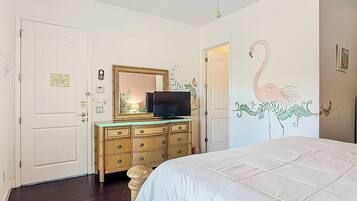 A bedroom with a bed, a dresser, a television, and a wall mural.
