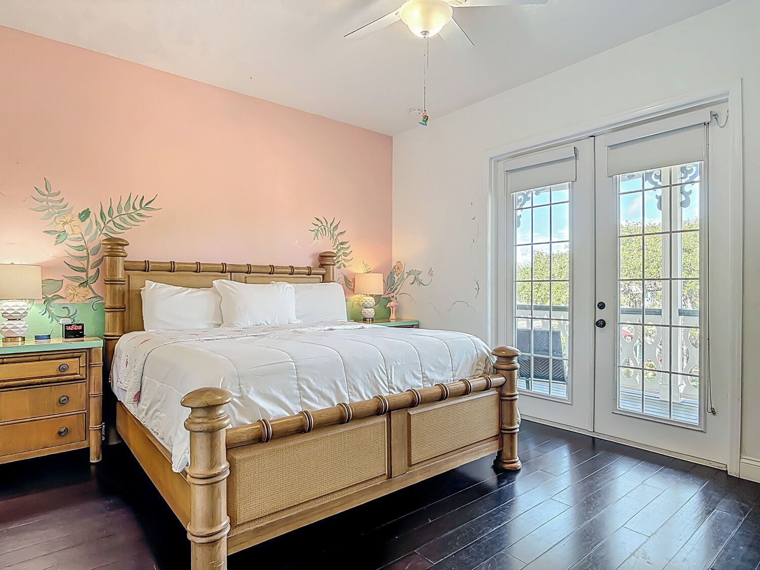 Une chambre à coucher avec un lit en bois, une table de chevet, une lampe et un mur décoré de motifs floraux.