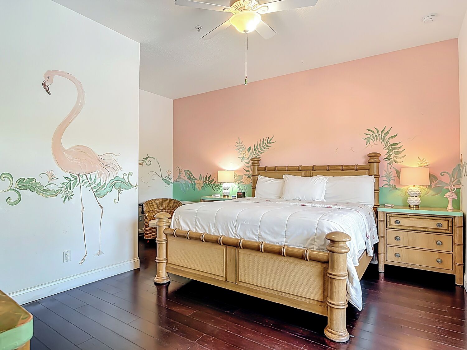 A bedroom with a bed, nightstands, a chair, and a ceiling fan.