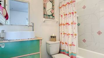 A bathroom with a white sink, a toilet, and a shower curtain with a flamingo pattern.