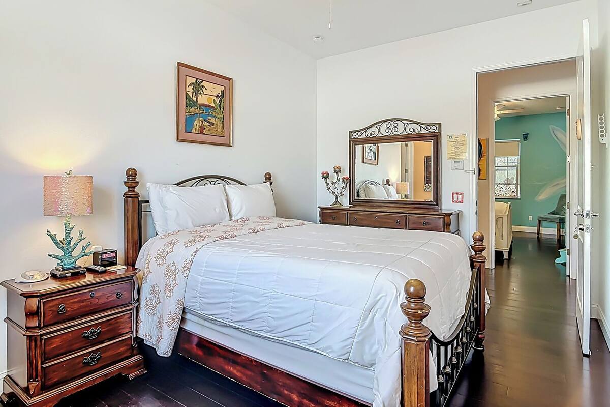 Una camera da letto con un letto, una cassettiera, uno specchio e opere d'arte alle pareti.