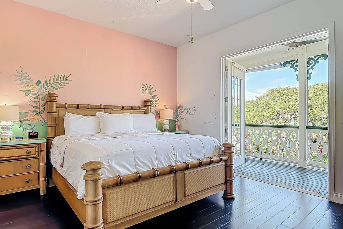 Camera da letto con un letto di legno, un comodino, una lampada e una parete decorata con motivi floreali.