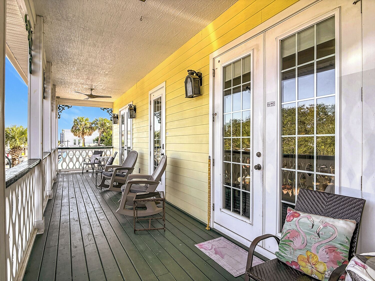 A porch with wooden flooring, outdoor seating, and a view of the street.