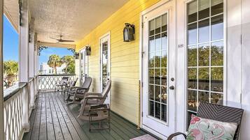 A porch with wooden flooring, outdoor seating, and a view of the street.