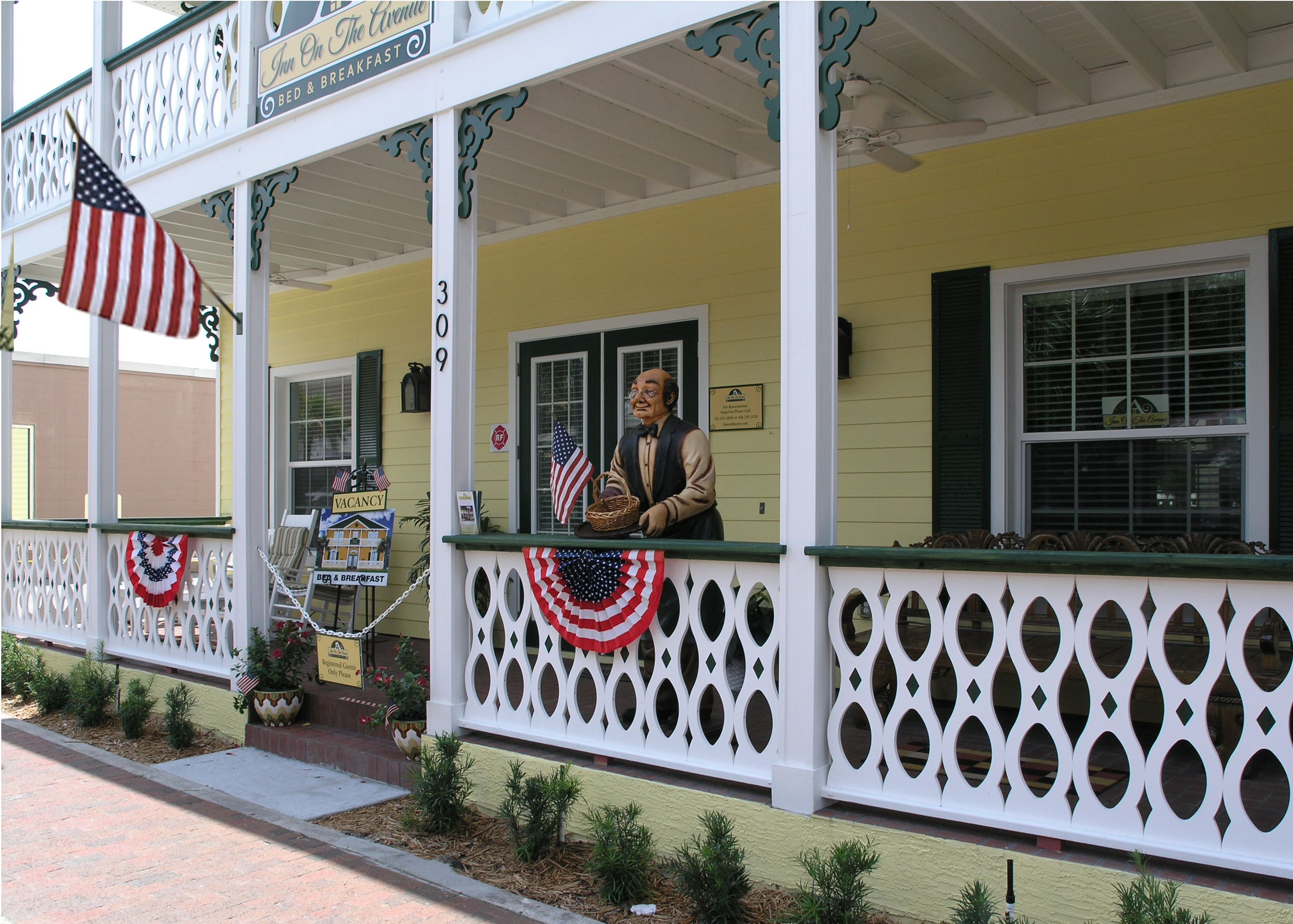 A building with a porch, American flags, and a sign indicating it is a bed and breakfast.