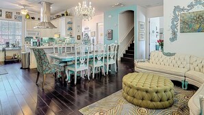A spacious living area with a dining table, chairs, a sofa, and a decorative ottoman. - Inn On the Avenue (New Smyrna Beach)