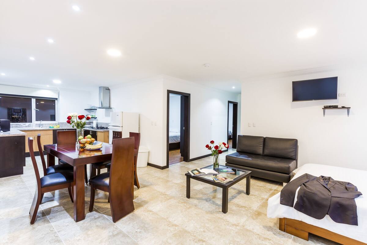 Una sala moderna con comedor, un sofá y un televisor de pantalla plana.
